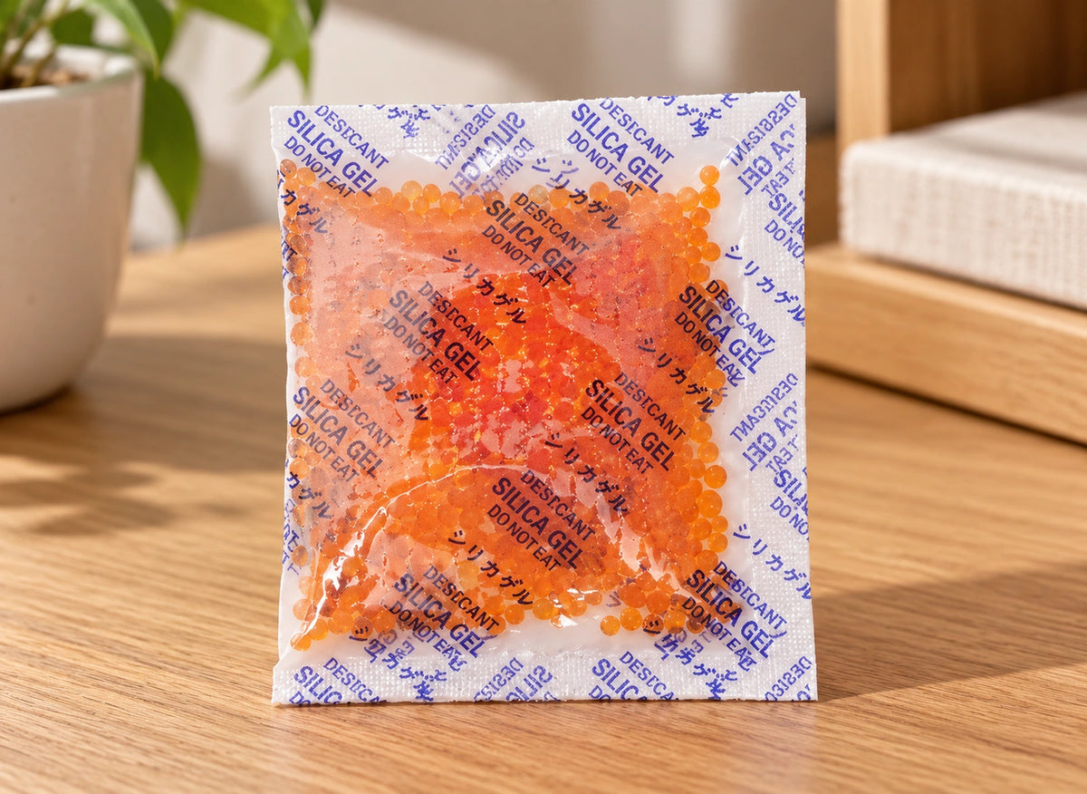Détail d’un sachet de gel de silice montrant des billes orange et la mention de ne pas ingérer